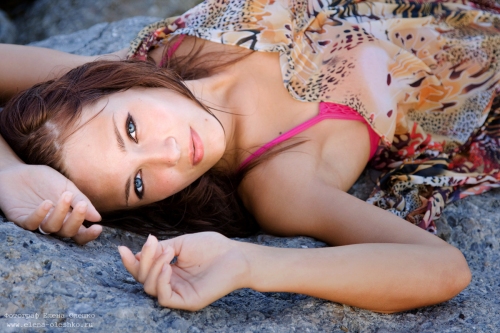 Portrait of a young blue-eyed woman lying on a rock